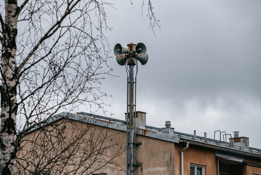 Varningssiren på ett hustak mot grå himmel
