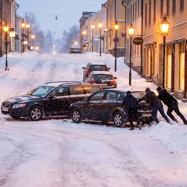 Människor knuffar bil som fastnat i snö